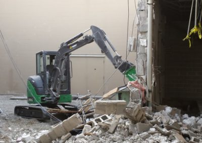 large equipment demoing concrete wall